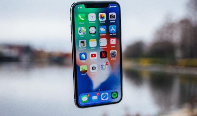 silver iPhone X floating over open palm